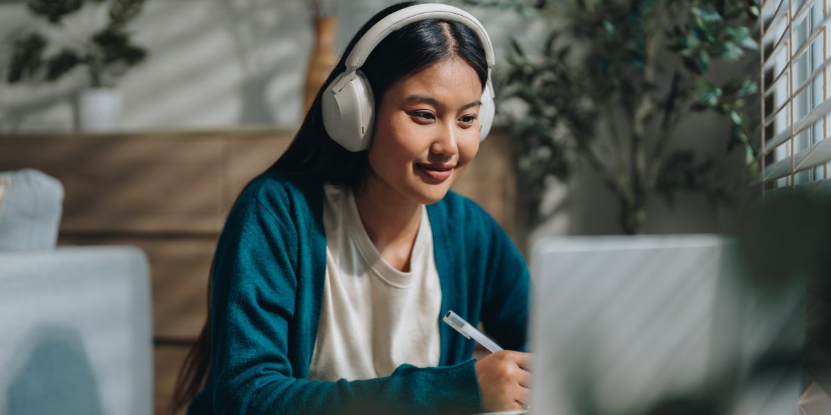 Woman enjoying her online class, attentively taking notes as she stays engaged and focused. With a sense of curiosity and dedication, she embraces the opportunity to learn from home and improve her knowledge