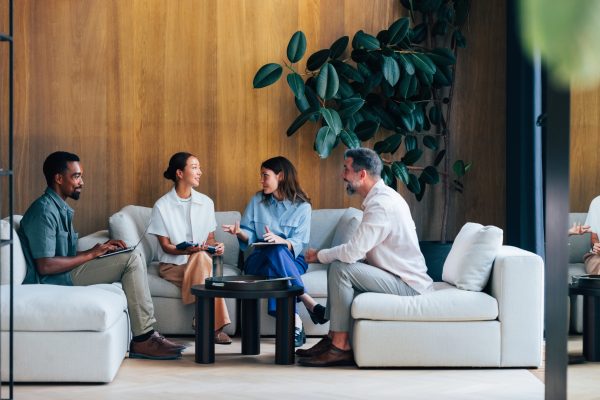 A group of four professionals engaging in a collaborative discussion in a stylish, modern lounge area. Ideal for business, teamwork, and professional environment concepts.